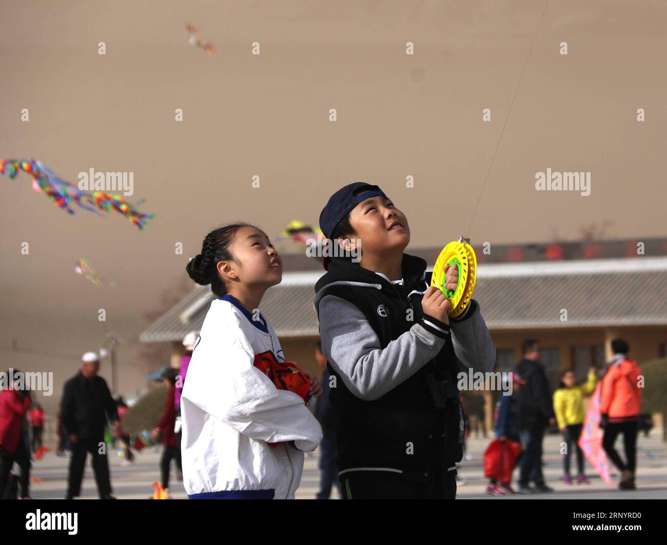 (180331) -- DUNHUANG, March 31, 2018 -- People fly kites at the scenic spot of the Crescent Spring, a crescent-shaped lake surrounded by deserts at the foot of the Mingsha Hill, in Dunhuang, northwest China s Gansu province, March 31, 2018. ) (dhf) CHINA-GANSU-DUNHUANG-KITE (CN) ZhangxXiaoliang PUBLICATIONxNOTxINxCHN Stock Photo