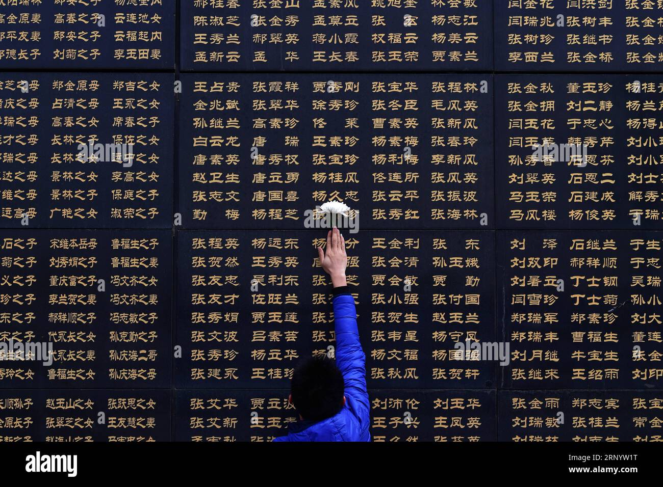 (180404) -- TANGSHAN, April 4, 2018 -- A well-wisher attaches a white chrysanthemum to a memorial wall in remembrance of victims in the 1976 Tangshan Earthquake in Tangshan, north China s Hebei Province, on April 4, 2018, one day before the Qingming Festival when the deceased are commemorated. ) (lmm) CHINA-HEBEI-EARTHQUAKE-VICTIM-REMEMBRANCE (CN) DongxJun PUBLICATIONxNOTxINxCHN Stock Photo
