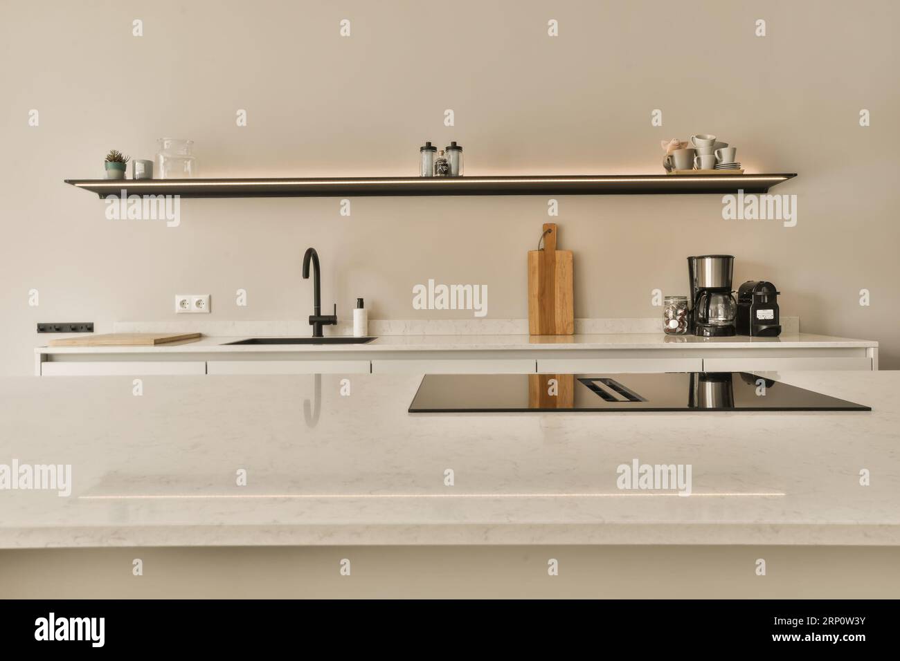 a kitchen with white marble counter tops and black metal shelvings on the wall behind it is a coffee machine Stock Photo