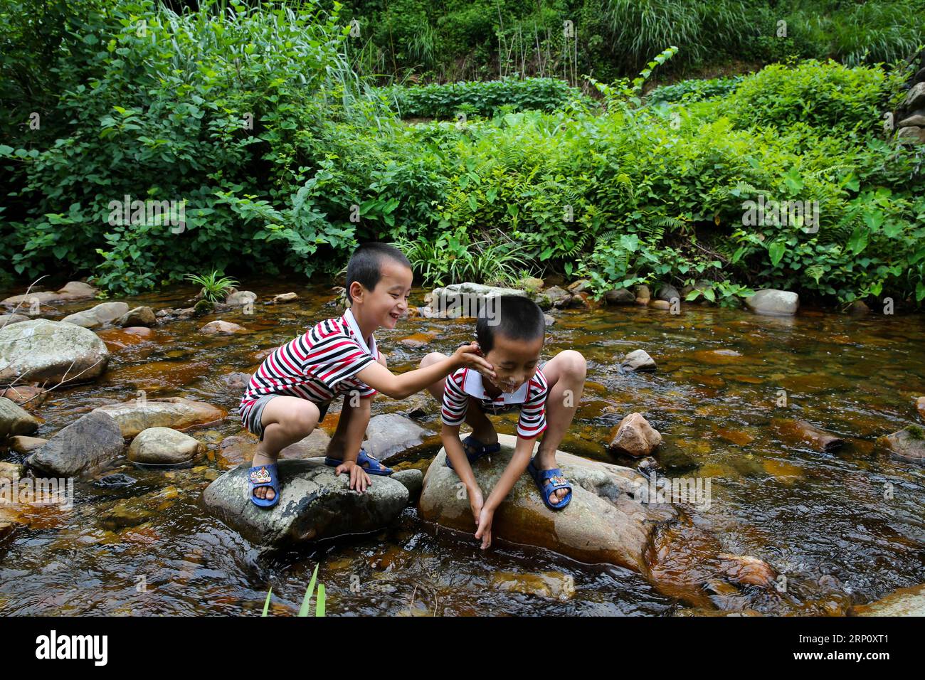 (180529) -- NANCHANG, May 29, 2018 -- Nine-year-old Huang Guanhao (L) and his twin brother Huang Guanping play by a stream in Suolong Village of Yudu County, east China s Jiangxi Province, May 23, 2018. With about 1,000 residents, Suolong Village has 29 cases of multiple births, a high rate considering the modest population size. ) (lmm) CHINA-JIANGXI-VILLAGE-MULTIPLE BIRTHS-TWINS-LIFE (CN) PanxSiwei PUBLICATIONxNOTxINxCHN Stock Photo