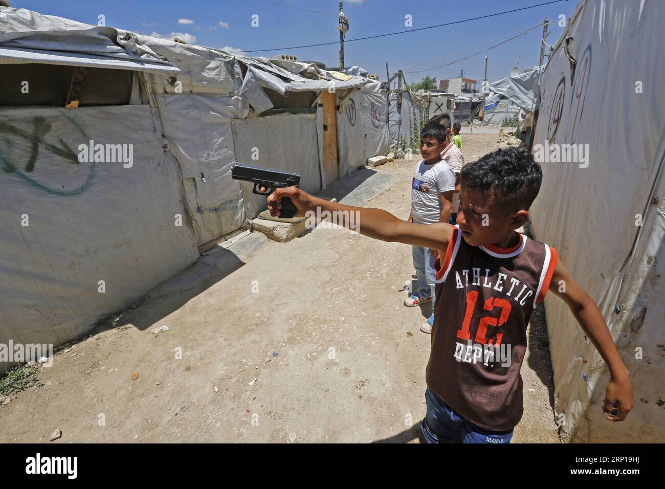 180619 -- BEIRUT, June 19, 2018 -- A refugee child holds a toy pistol at a Syrian refugee camp in Bar Elias, Bekaa Valley, eastern Lebanon, on June 19, 2018, ahead of World Refugee Day. After years of war in Syria, Syrian refugees continued their lives in Lebanon. The number of people forcibly displaced due to wars, other violence, and persecution worldwide reached a new high in 2017 to 68.5 million, 2.9 million more than the year before, the UN refugee agency, UNHCR, said Tuesday.  LEBANON-BEKAA VALLEY-BAR ELIAS-SYRIAN REFUGEE CAMP BilalxJawich PUBLICATIONxNOTxINxCHN Stock Photo