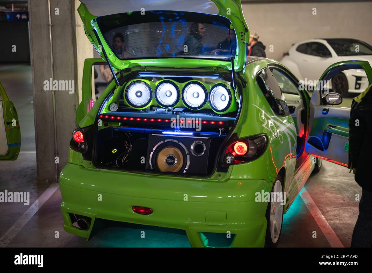 A tuned green Peugeot 206 with the trunk open and full of loudspeakers playing music at a tuning car meetup Stock Photo