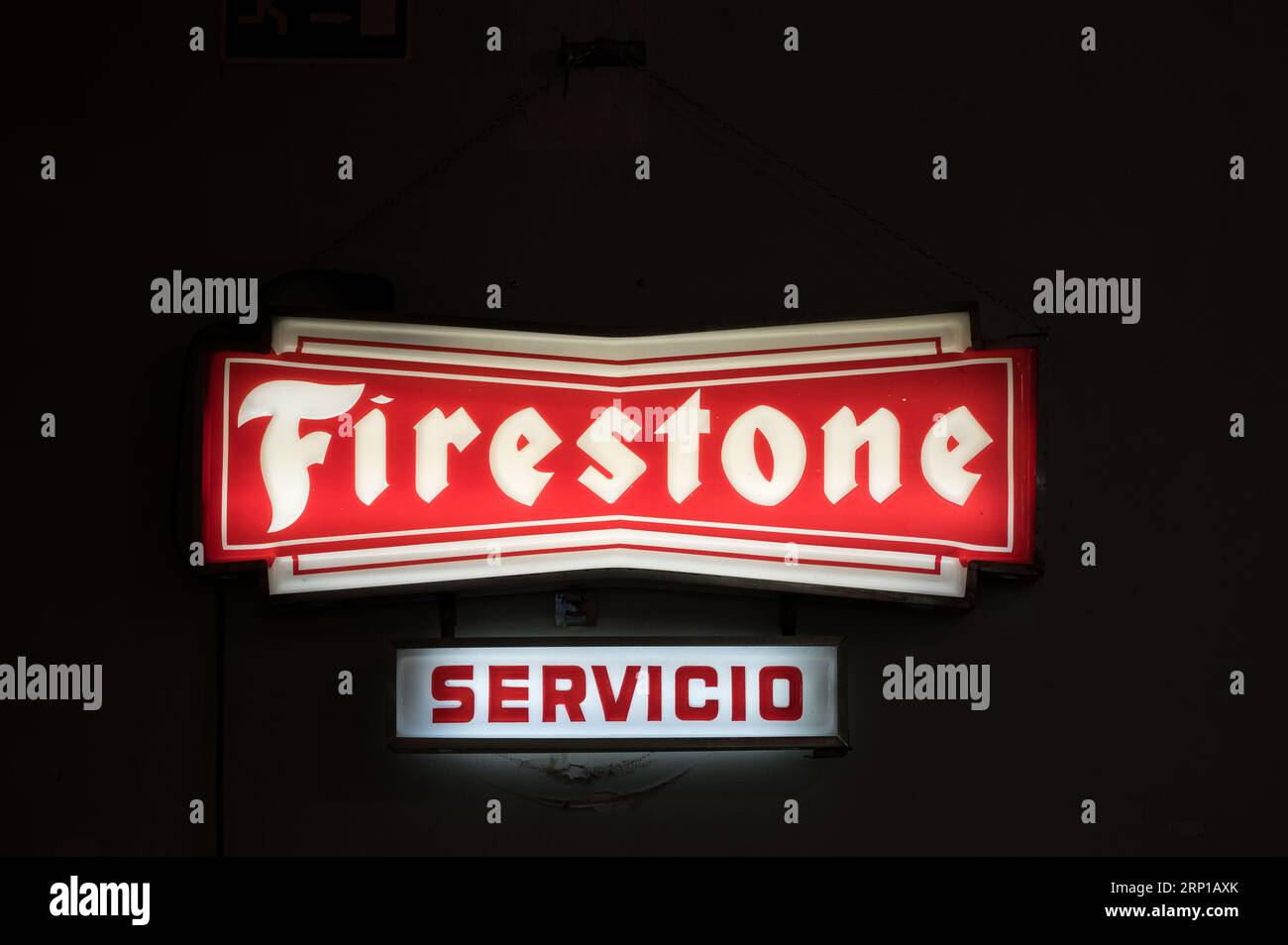 A closeup of an old illuminated sign for the Firestone service station in an old workshop Stock Photo