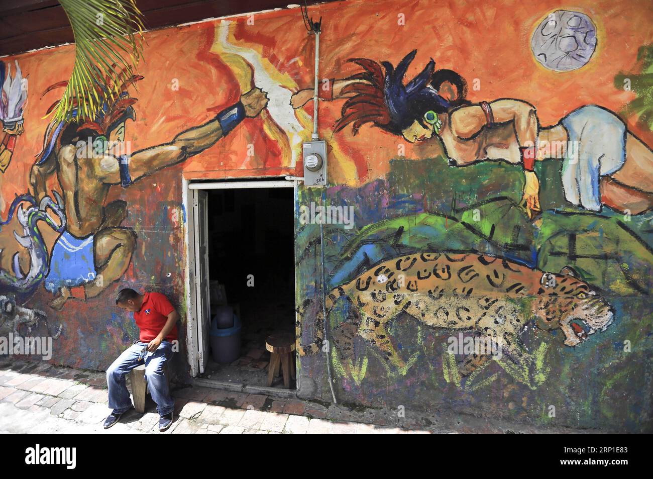 (180630) -- SAN JUAN DE FLORES, June 30, 2018 -- A man sits in front of a house painted with mural in the municipality of San Juan de Flores, department of Francisco Morazan, Honduras, on June 29, 2018. ) (djj) HONDURAS-SAN JUAN DE FLORES-MURALS RafaelxOchoa PUBLICATIONxNOTxINxCHN Stock Photo