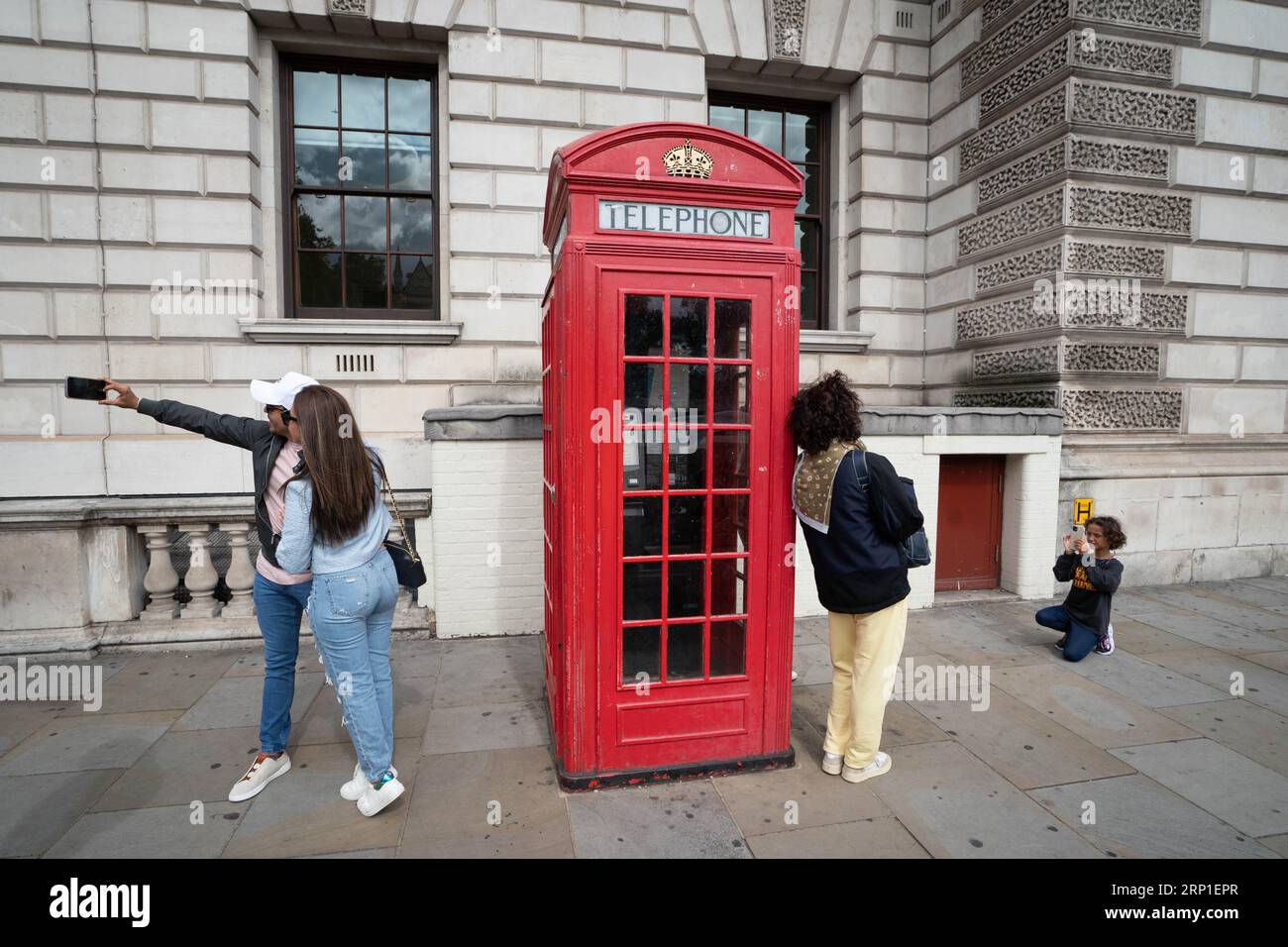 Tourists and visitors to London have their photo taken beside a red phone box at Parliament Square in Westminster, as the popularity of the famous booths endures in the social media age as they approach their 100th anniversary. The famous red phone box was designed by architect Sir Giles Gilbert Scott for a competition in 1924. Picture date: Tuesday August 15, 2023. Stock Photo