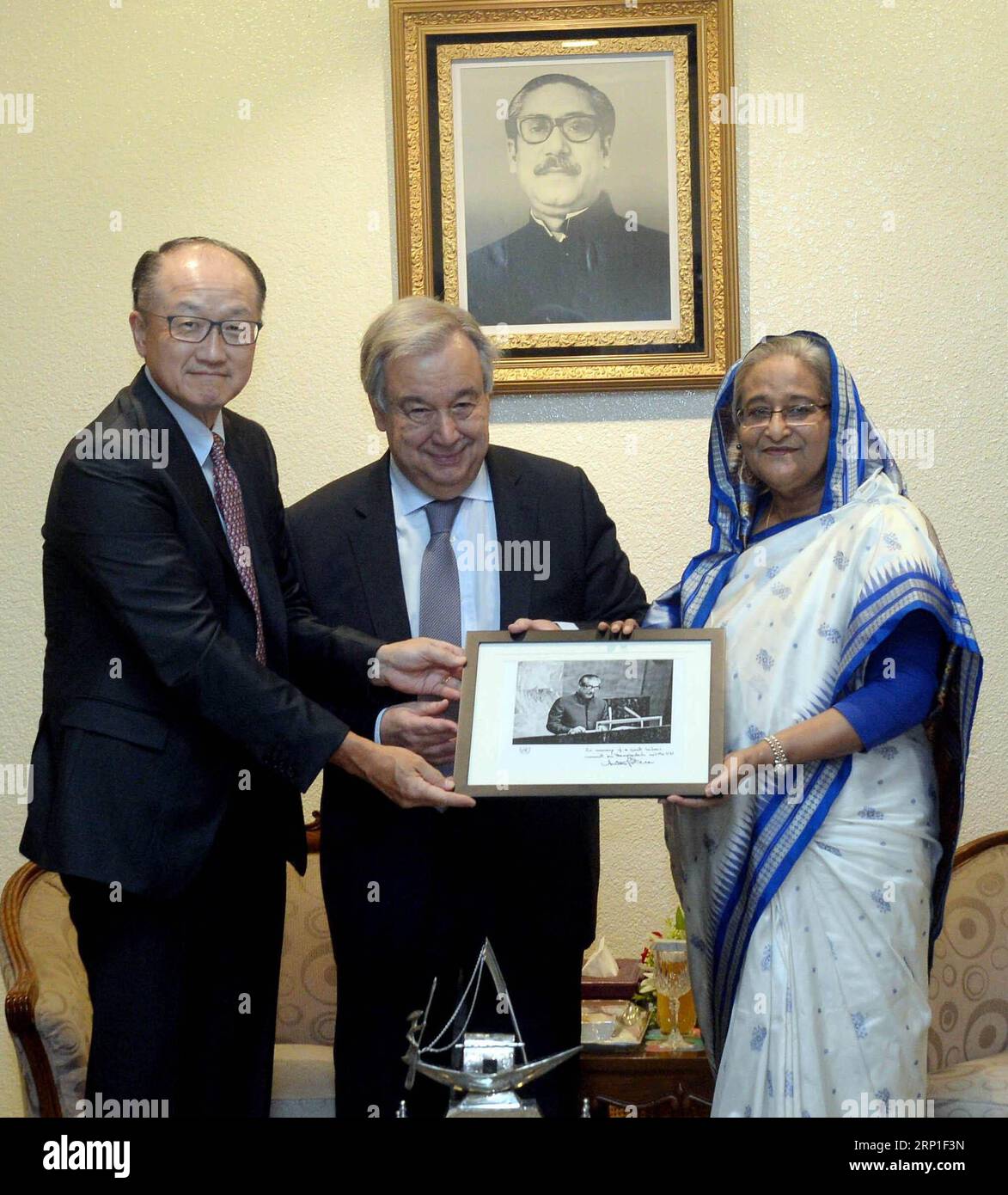 (180701) -- DHAKA, July 1, 2018 () -- United Nations Secretary-General Antonio Guterres (C) and World Bank President Jim Yong Kim (L) present to Bangladeshi Prime Minister Sheikh Hasina a photo of her father Bangabandhu Sheikh Mujibur Rahman, founding father of Bangladesh, in Dhaka, Bangladesh, on July 1, 2018. U.N. Secretary-General Antonio Guterres arrived here early Sunday in a joint visit with World Bank President Jim Yong Kim to assess the needs for the nearly one million Rohingya refugees driven from their homes in Myanmar. () BANGLADESH-DHAKA-UN-WORLD BANK-JOINT VISIT Xinhua PUBLICATION Stock Photo