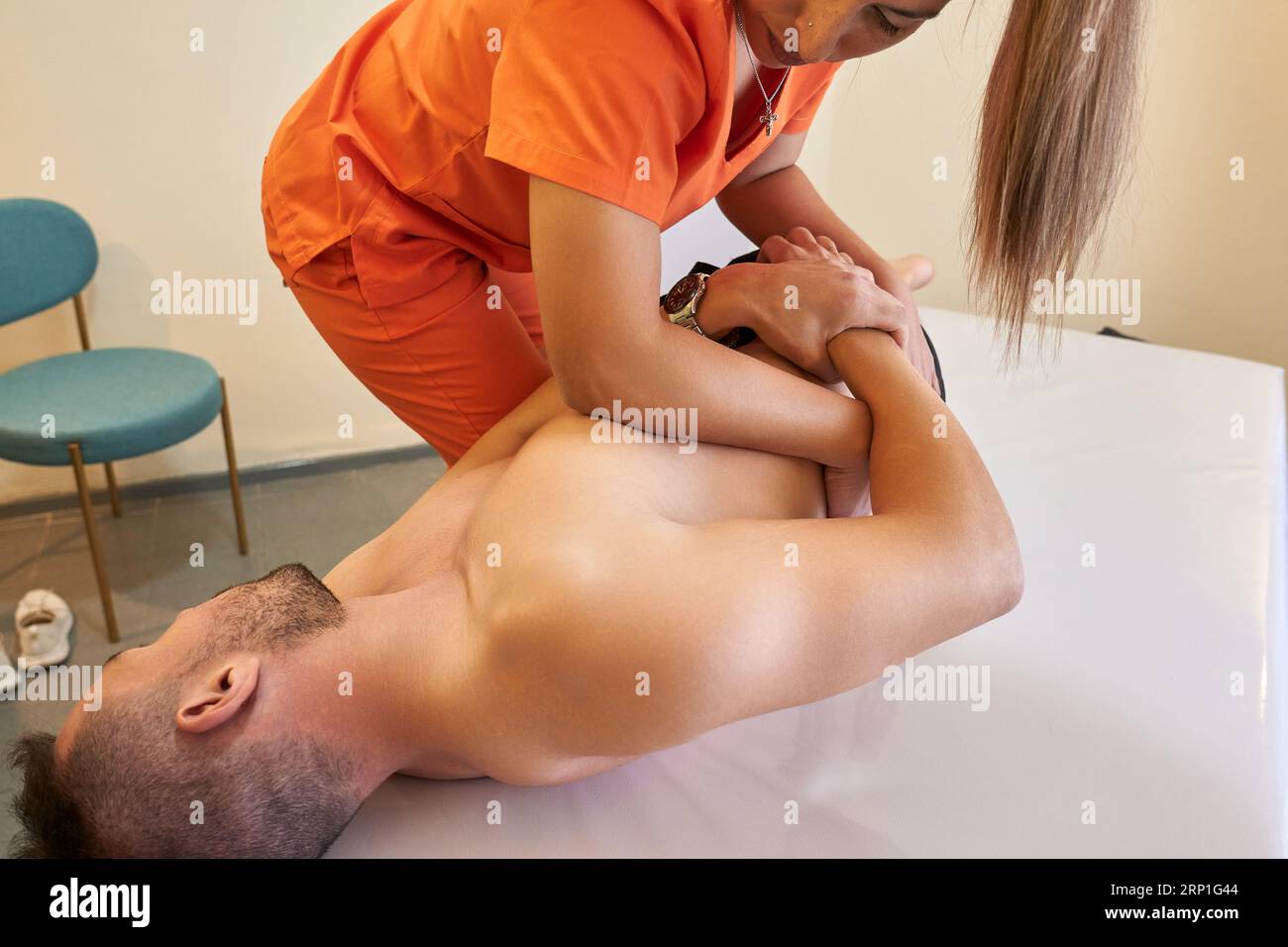 Female doctor readjusting a male patient's lumbar spine Stock Photo