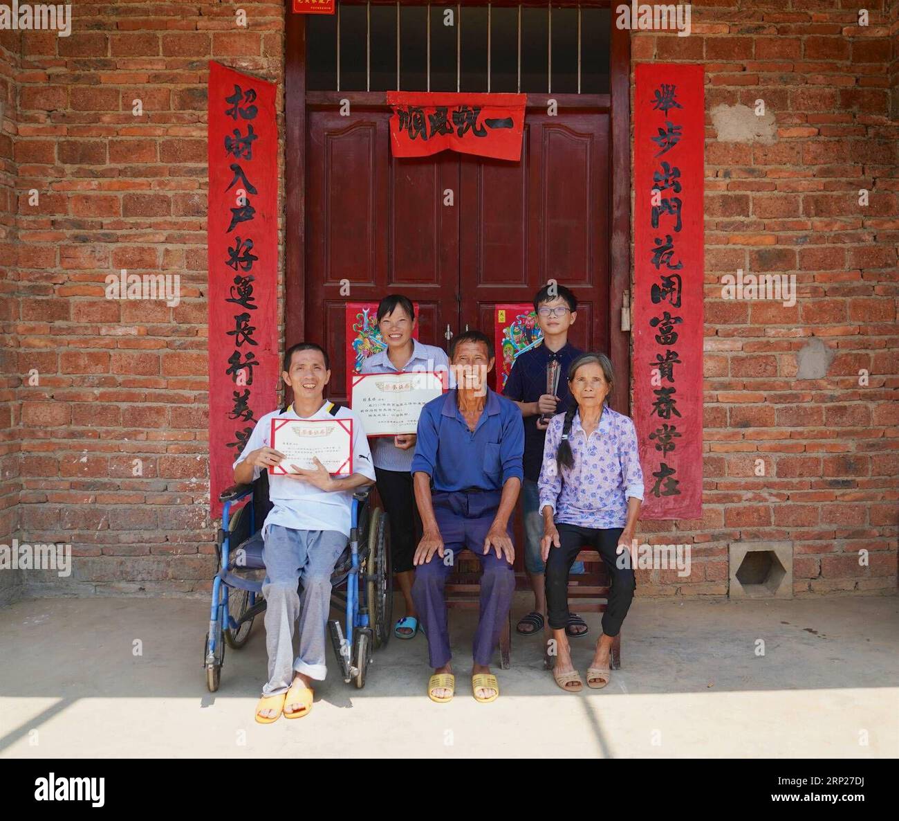 (180823) -- NANCHANG, Aug. 23, 2018 -- Zhang Chunmei (2nd L) and her husband (1st L) take photos with their families in front of their home in Wan an County, east China s Jiangxi Province, Aug. 22, 2018. Zhang Chunmei has been providing for her family after her husband, Xu Liliang, was diagnosed with Parkinson s disease in 2009. Thanks to her hardworking and the help from others, her family s living standard has improved. Her family decided to take a wedding dress photo to mark their 15 years wedding anniversary. ) (zyd) CHINA-JIANGXI-WEDDING ANNIVERSARY-POVERTY (CN) HuxChenhuan PUBLICATIONxNO Stock Photo