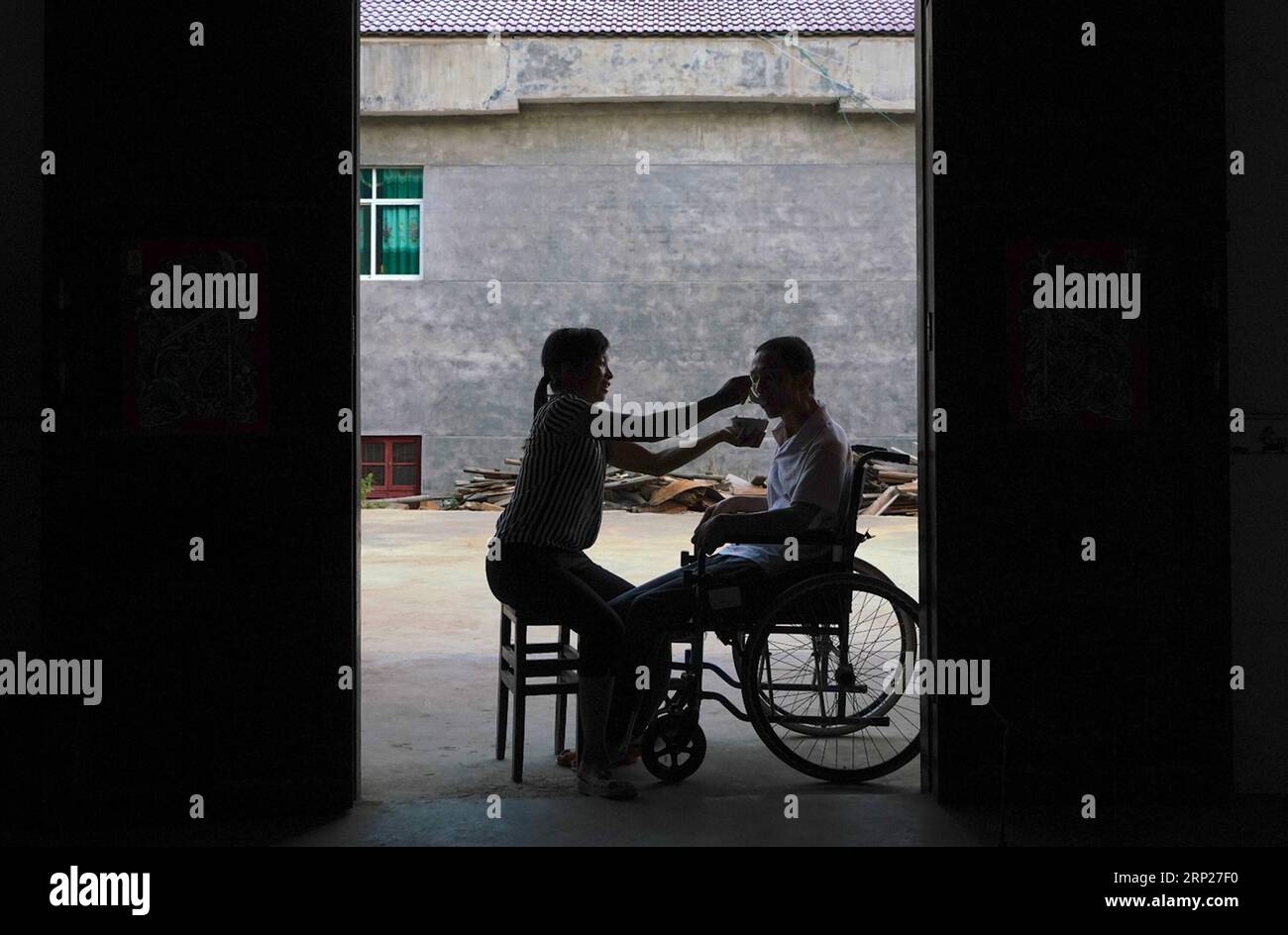 (180823) -- NANCHANG, Aug. 23, 2018 -- Zhang Chunmei helps her husband eat at their home in Wan an County, east China s Jiangxi Province, Aug. 21, 2018. Zhang Chunmei has been providing for her family after her husband, Xu Liliang, was diagnosed with Parkinson s disease in 2009. Thanks to her hardworking and the help from others, her family s living standard has improved. Her family decided to take a wedding dress photo to mark their 15 years wedding anniversary. ) (zyd) CHINA-JIANGXI-WEDDING ANNIVERSARY-POVERTY (CN) HuxChenhuan PUBLICATIONxNOTxINxCHN Stock Photo