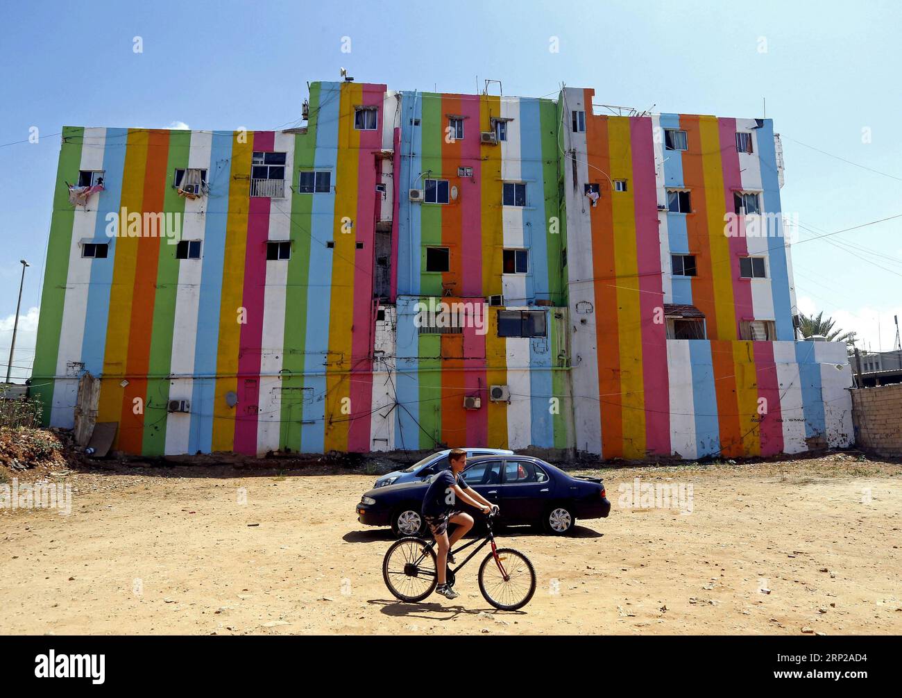 (180827) -- OUZAI, Aug. 27, 2018 -- A boy rides by buildings with colorful paintings in Ouzai, south of Beirut, Lebanon, on Aug. 26, 2018. ) (jmmn) LEBANON-OUZAI-BUILDINGS BilalxJawich PUBLICATIONxNOTxINxCHN Stock Photo