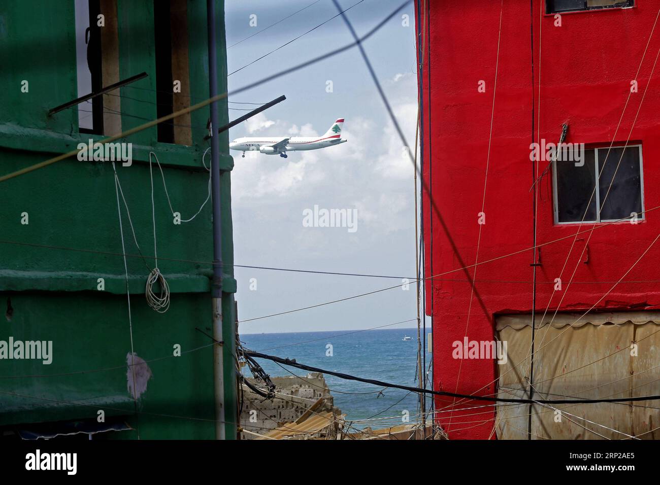 (180827) -- OUZAI, Aug. 27, 2018 -- A plane flies by buildings with colorful paintings in Ouzai, south of Beirut, Lebanon, on Aug. 26, 2018. ) (jmmn) LEBANON-OUZAI-BUILDINGS BilalxJawich PUBLICATIONxNOTxINxCHN Stock Photo