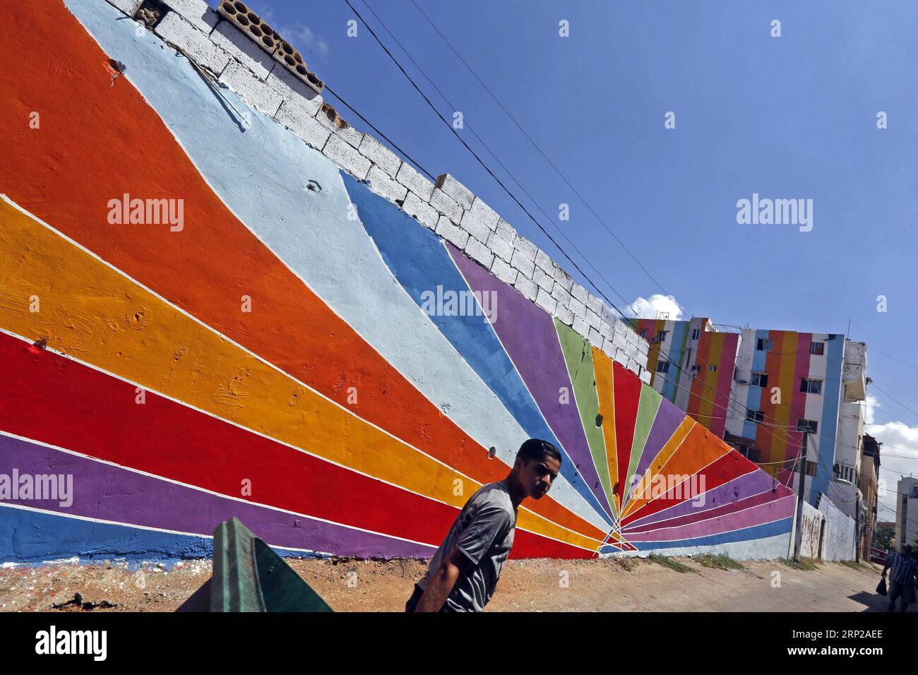 (180827) -- OUZAI, Aug. 27, 2018 -- A man walks past buildings with colorful paintings in Ouzai, south of Beirut, Lebanon, on Aug. 26, 2018. ) (jmmn) LEBANON-OUZAI-BUILDINGS BilalxJawich PUBLICATIONxNOTxINxCHN Stock Photo