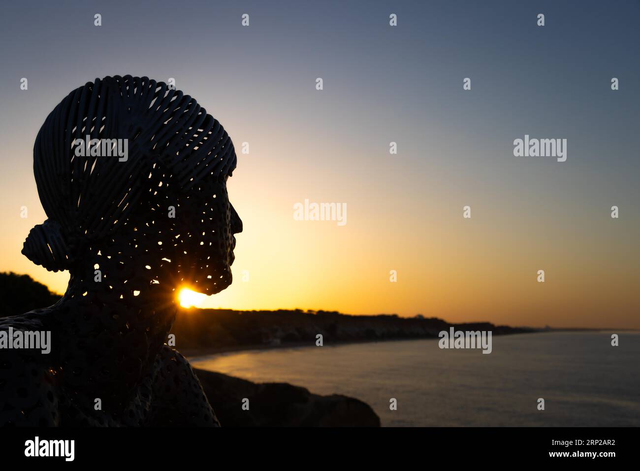 A metal sculpture by artist Carlos de Oliveira Correia looks out over the Atlantic Ocean at sunrise on the viewing platform at Olhos des Augua beach Stock Photo