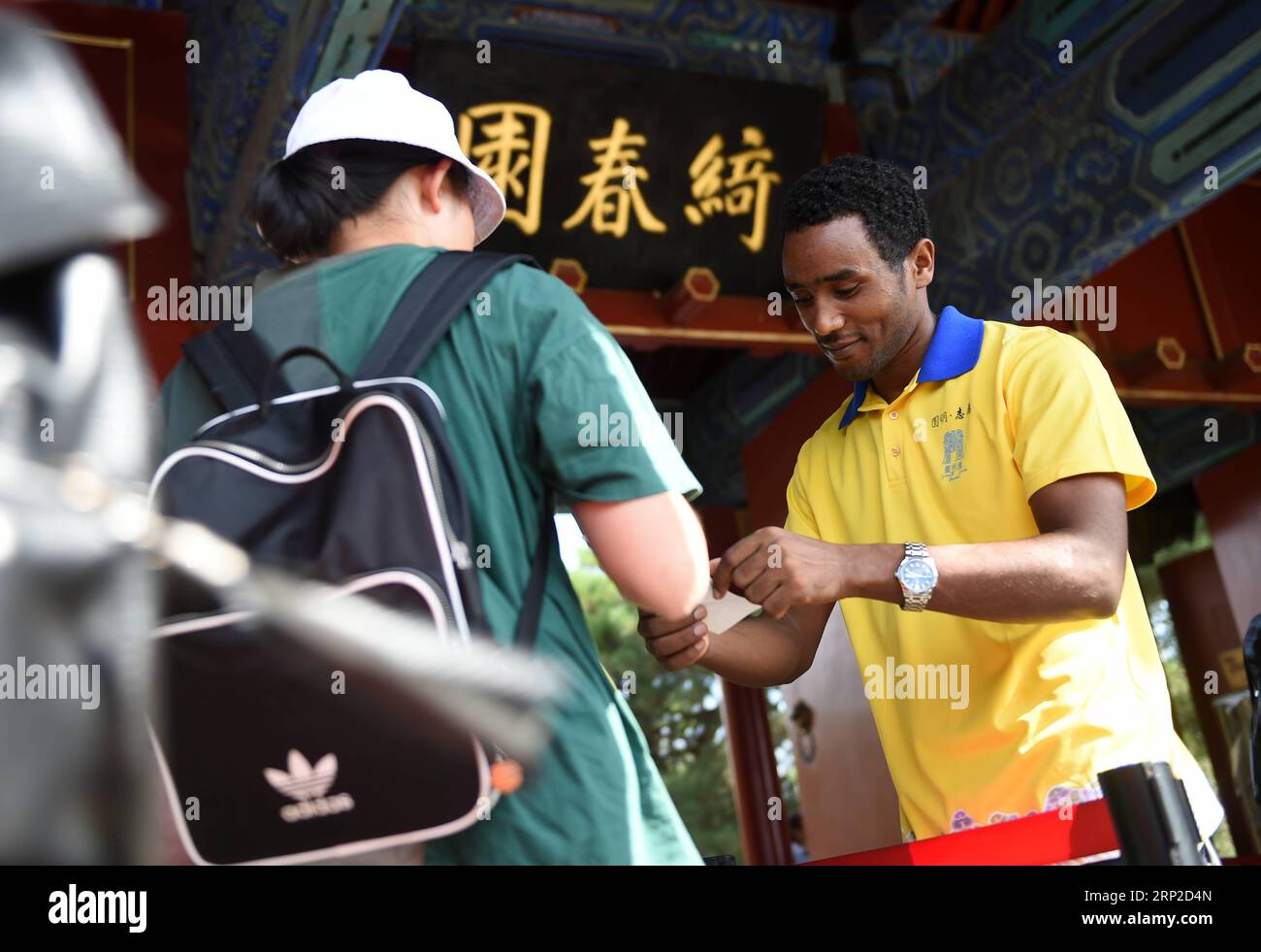 (180831) -- BEIJING, Aug. 31, 2018 -- Endale Leqesse (R), an Ethiopian student studying in China and a volunteer at Yuanmingyuan, or the Old Summer Palace, works at one of the park s entrances in Beijing, capital of China, Aug. 31, 2018. Yuanmingyuan set up its volunteer team in 2017 and has been recruiting volunteers from the public. In July 2018, about 20 overseas students from Africa joined the team to provide tourist services. ) (lmm) CHINA-BEIJING-YUANMINGYUAN PARK-AFRICAN VOLUNTEERS (CN) LuoxXiaoguang PUBLICATIONxNOTxINxCHN Stock Photo