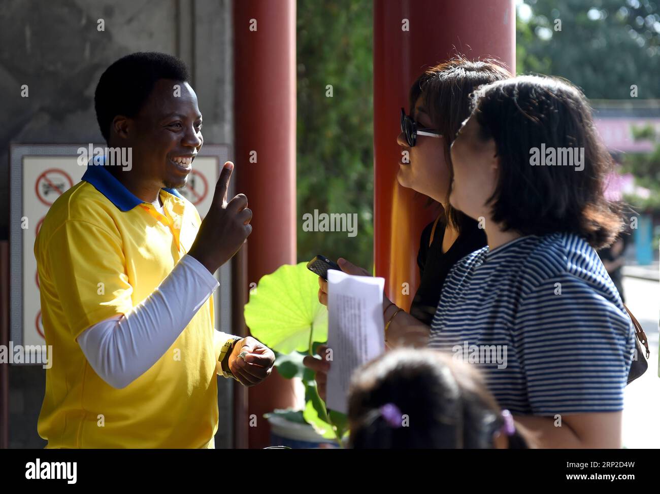 (180831) -- BEIJING, Aug. 31, 2018 -- Felicien Ieivvzimana (1st L), a Rwandan student studying in China and a volunteer at Yuanmingyuan, or the Old Summer Palace, talks with tourists at one of the park s entrances in Beijing, capital of China, Aug. 31, 2018. Yuanmingyuan set up its volunteer team in 2017 and has been recruiting volunteers from the public. In July 2018, about 20 overseas students from Africa joined the team to provide tourist services. ) (lmm) CHINA-BEIJING-YUANMINGYUAN PARK-AFRICAN VOLUNTEERS (CN) LuoxXiaoguang PUBLICATIONxNOTxINxCHN Stock Photo