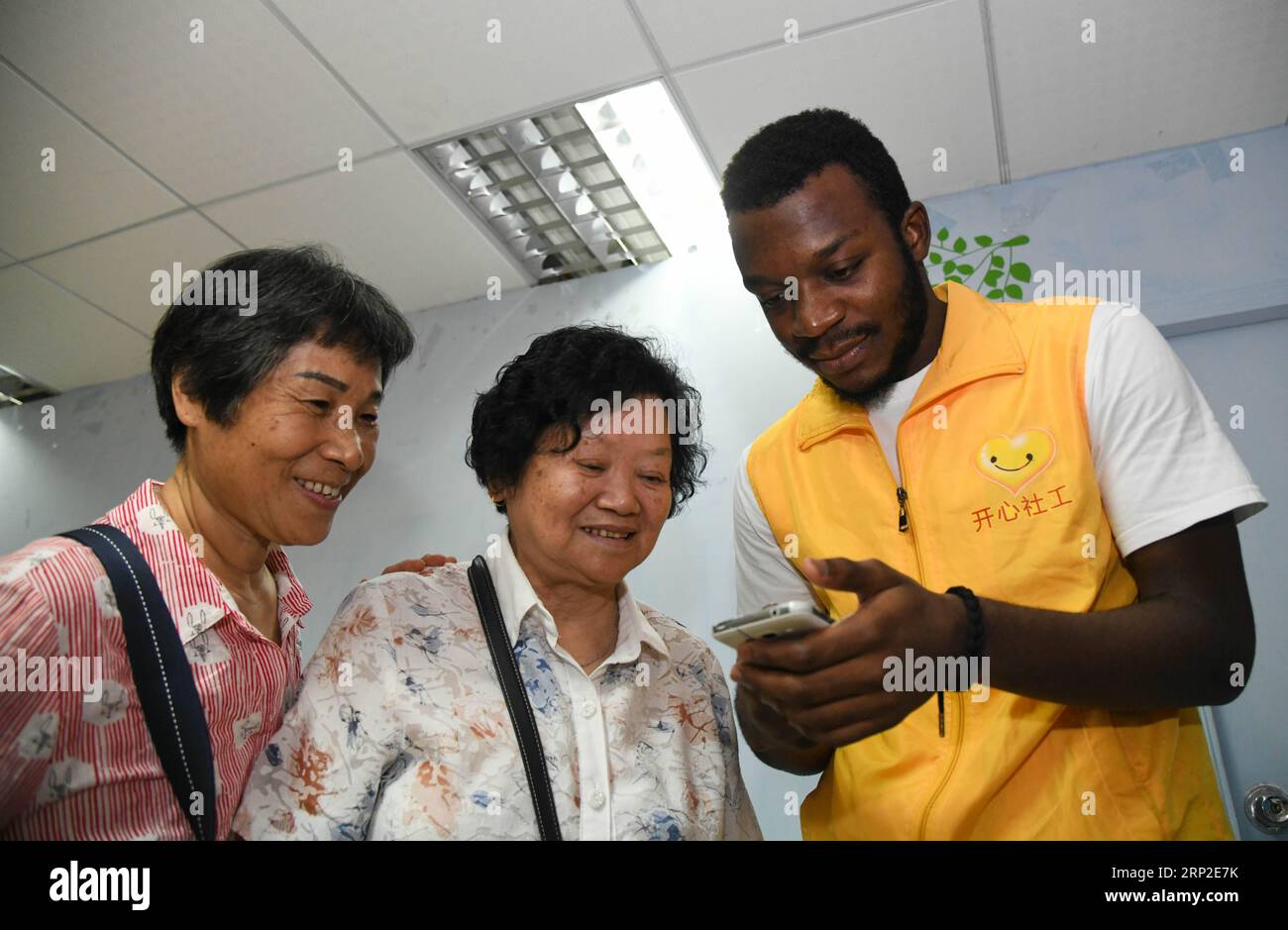 (180901) -- GUANGZHOU, Sept. 1, 2018 -- African student Kabey Heritier Lweny (1st R) helps Chinese senior citizens install a smartphone translation app in Guangzhou, south China s Guangdong Province, Aug. 29, 2018. Kabey, who comes from the Democratic Republic of Congo, came to Guangdong University of Technology as a Chinese language major about a year ago. The rich Chinese cuisine and culture have always appealed to him, but it s by taking part in various volunteer activities that has made him embrace the life in Guangzhou ever more closely. I grew to learn more about the Chinese traditions a Stock Photo