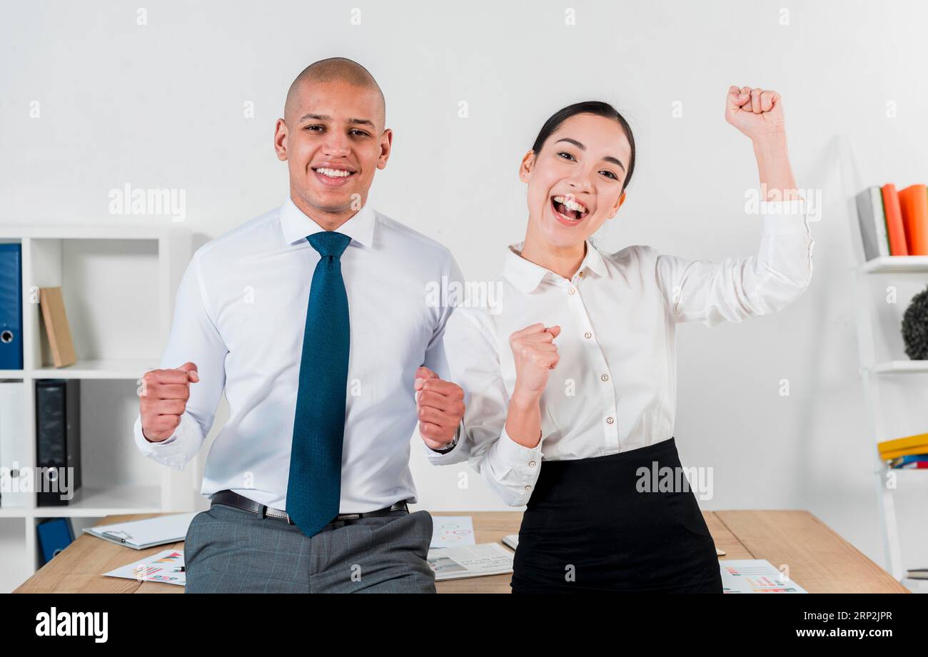 Excited overjoyed young business couple standing front table workplace Stock Photo