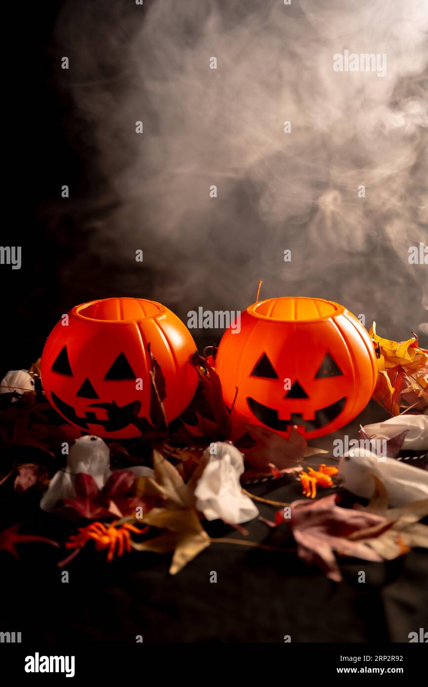 Halloween pumpkins over autumn leaves and ghosts with smoke on a black ...