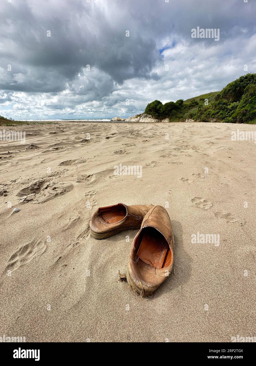 Human waste in nature. Old men's shoes on the beach. Beach rubbish Stock Photo