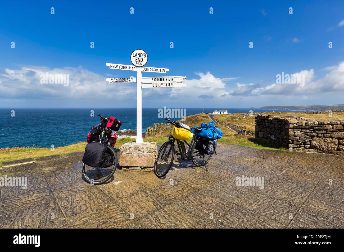 Two e-bikes at the famous signpost to New York, John o' Groats and the Isles of Scilly, Land's End, Lands End, Penzance, Penwith Peninsula, Cornwall Stock Photo