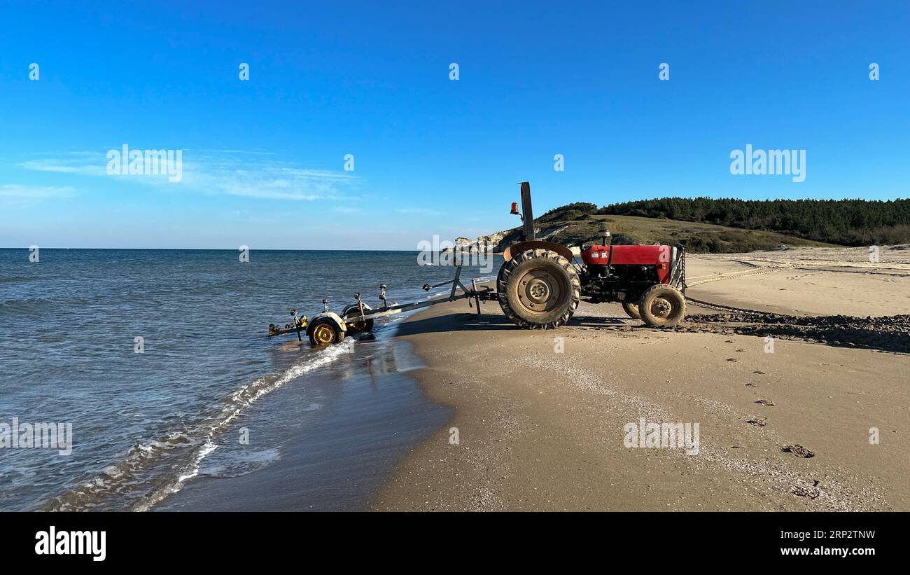 Boat trailer and tractor. Trailer used for launching boats from the beach to the sea Stock Photo