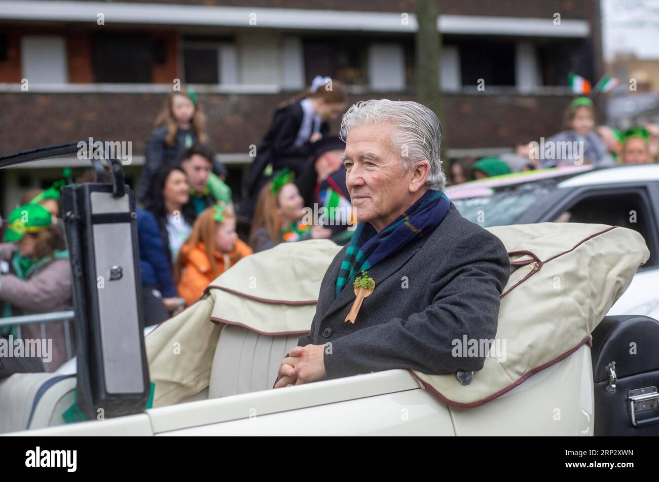 Actor Patrick Duffy sits in an old style carwaiting to be driven through the centre of Dublin for the St Patrick's day parade. Dublin, Ireland Stock Photo