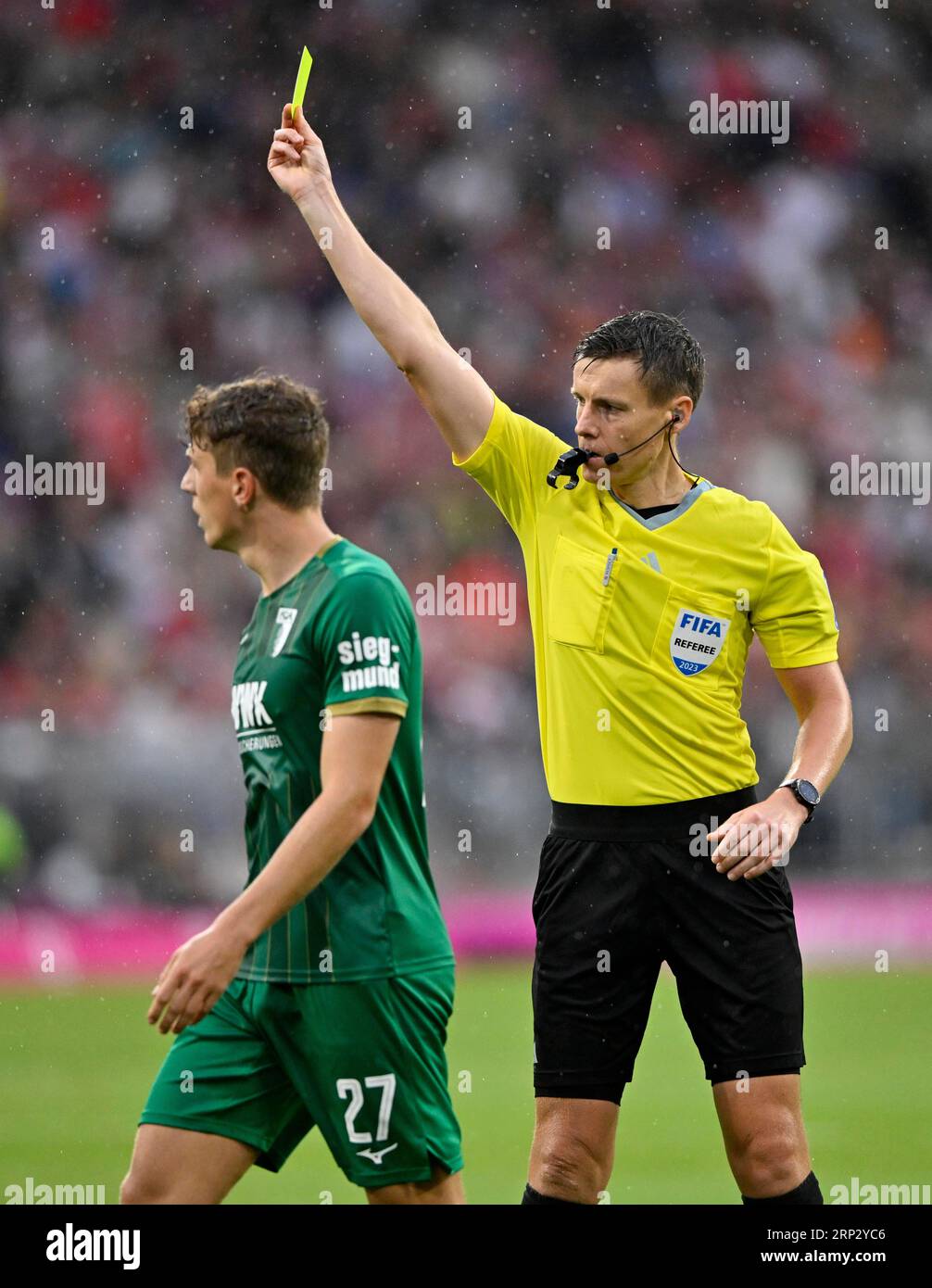 Referee Daniel Siebert shows Arne Engels FC Augsburg FCA (27) yellow
