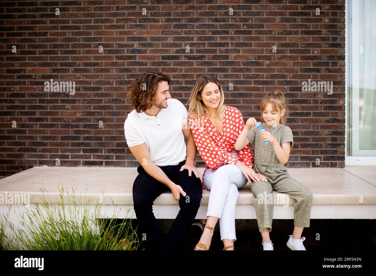 Family with a mother, father and daughter sitting outside on steps of a