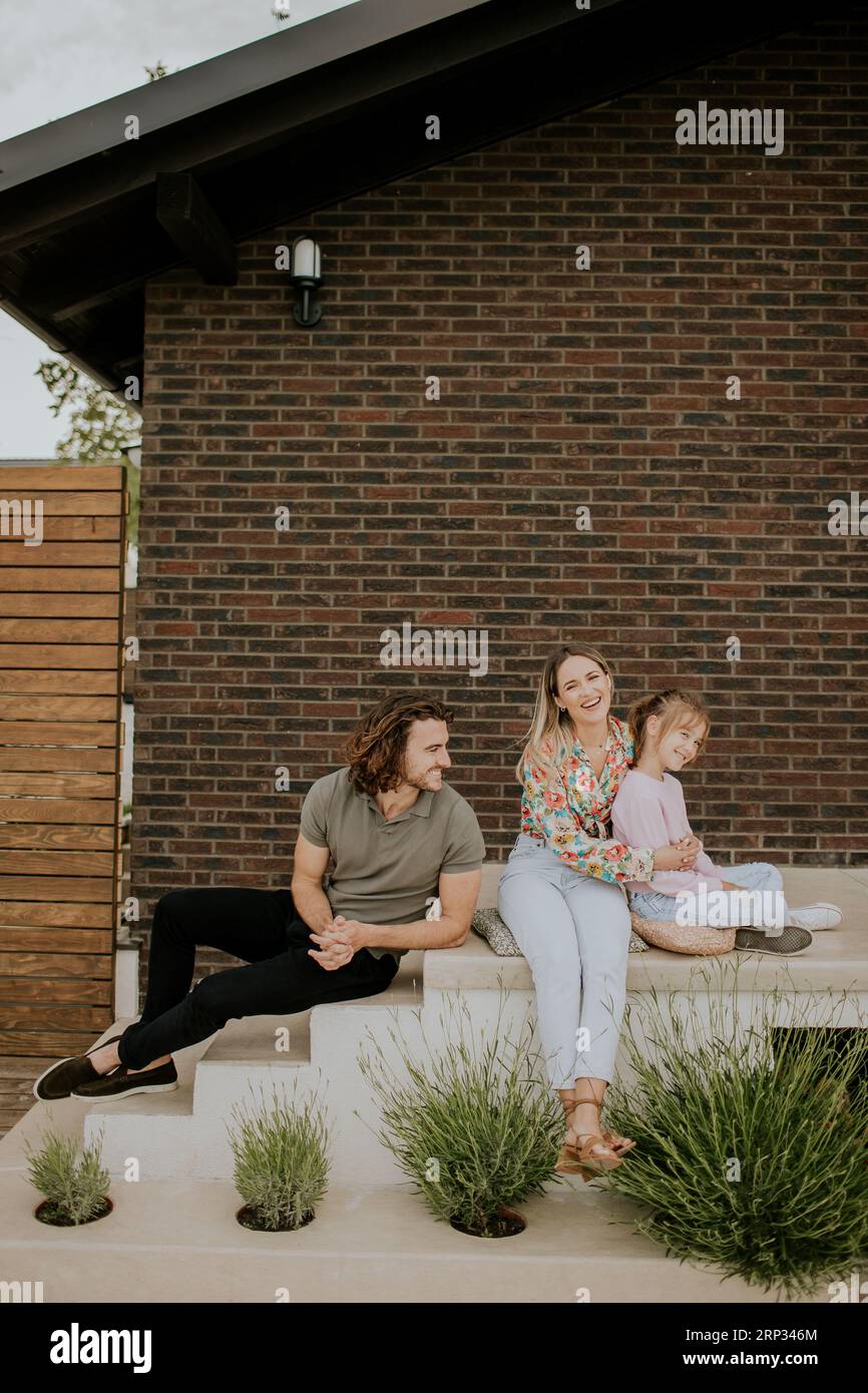 Family with a mother, father and daughter sitting outside on steps of a