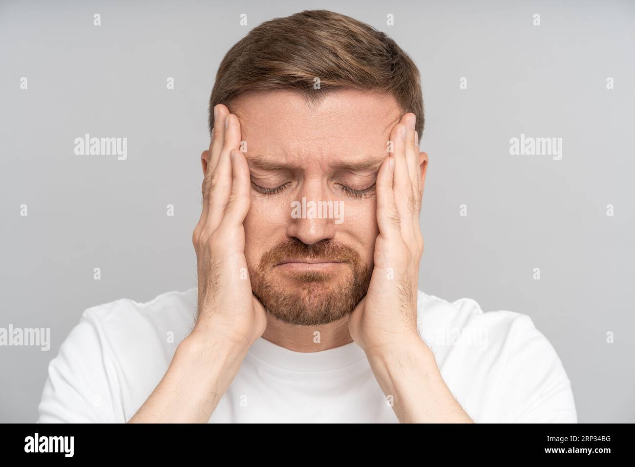 Portrait tired exhausted man feels headache holding face hands with
