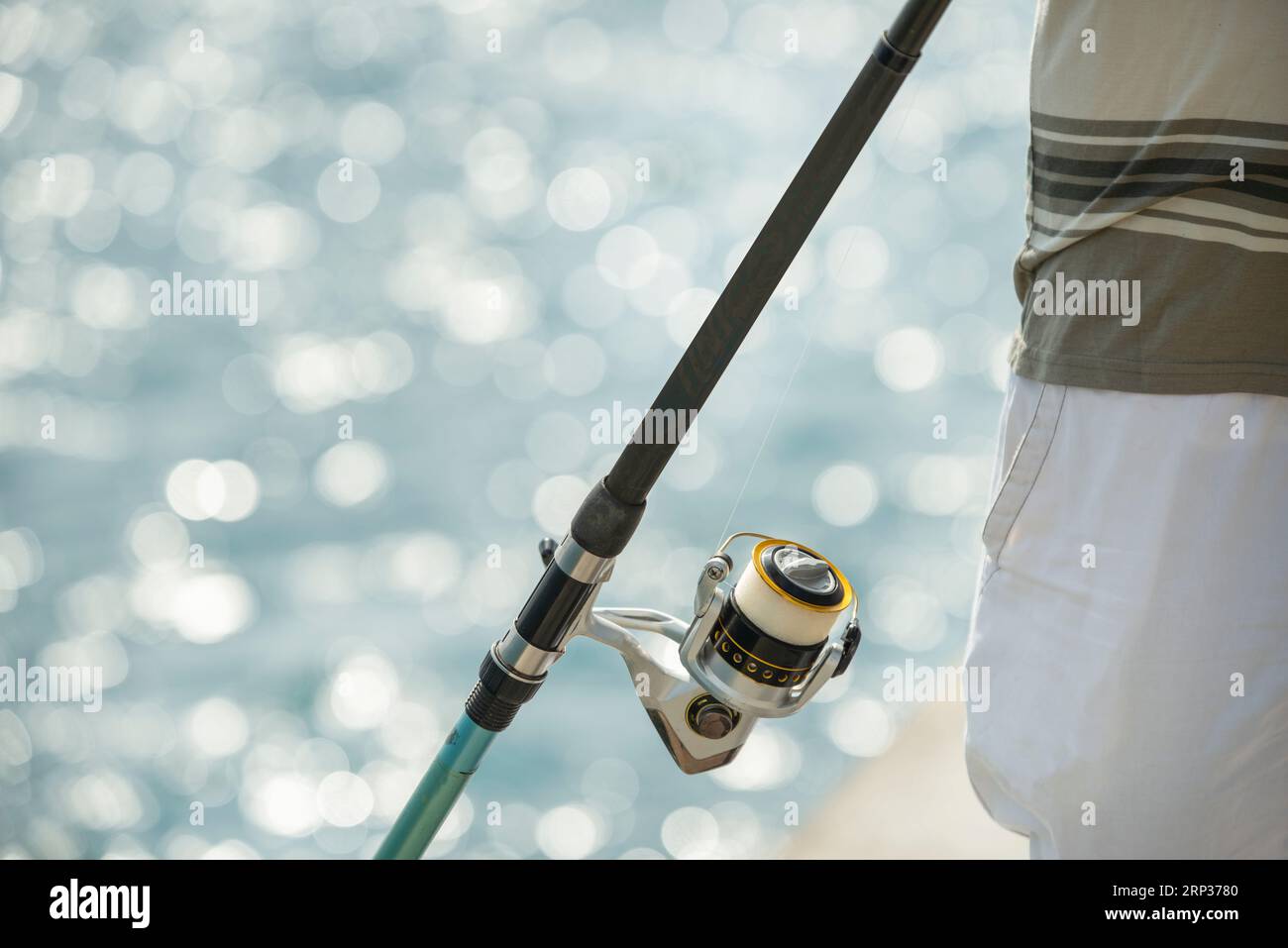 A fishing rod with a reel with white line on the seashore Stock Photo -  Alamy