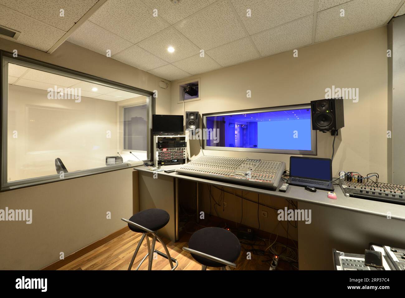 Mixing consoles in a small recording studio with several windows Stock