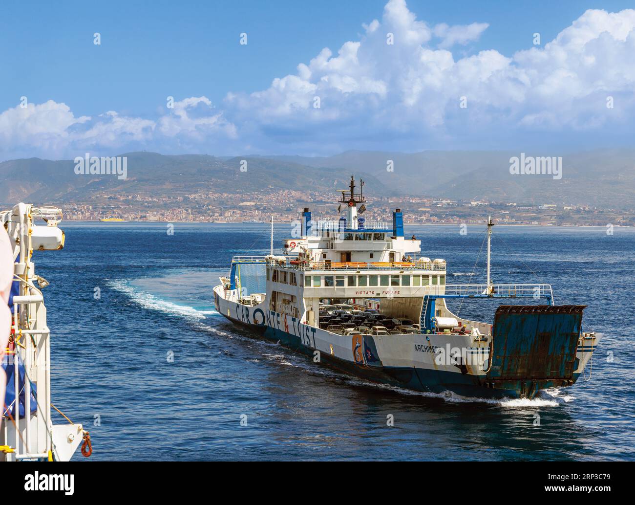 Car ferry in the Strait of Messina approaching Villa San Giovanni, Calabria, Italy from Messina, Sicily, seen in background. Stock Photo
