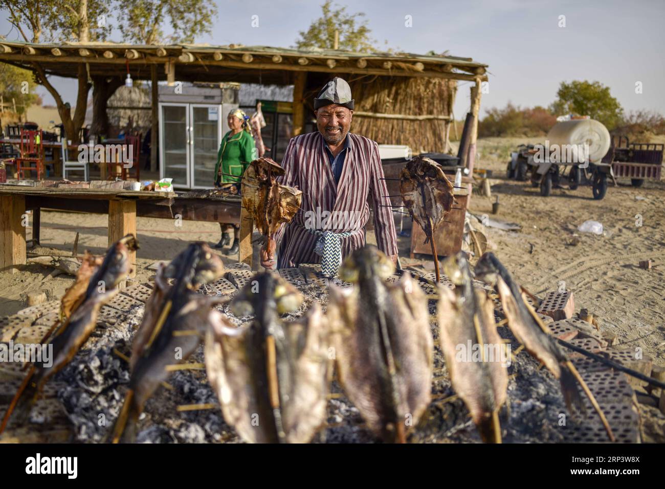 (181017) -- YULI, Oct. 17, 2018 (Xinhua) -- A resident makes roast fish at the Lop Nur People Village of Yuli County, northwest China s Xinjiang Uygur Autonomous Region, Oct. 16, 2018. The Lop Nur people depended basically on fishing for livelihood and developed a distinct culture based on their special lifestyle. Located in Tarim basin, Yuli is known for its natural scenery and ethnic culture and keeps attracting numerous tourists from at home and abroad. From Oct. 1 to 16, 2018, Yuli County has received more than 230,000 visitors, with a year-on-year increase of 31.46 percent. (Xinhua/Zhao G Stock Photo