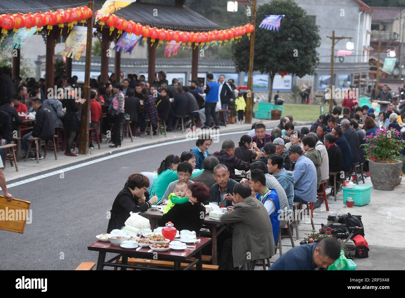 (181018) -- TONGLU, Oct. 18, 2018 (Xinhua) -- Local residents and tourists enjoy the long-table banquet held at Longfeng Ethnic Village in Eshan Township of the She ethnic group of Tonglu County, east China s Zhejiang Province, Oct. 17, 2018. A total of 100 tables of delicacies were presented at the long-table banquet along a street held at the village, attracting local residents as well as tourists to enjoy the food of the She ethnic group. (Xinhua/Huang Zongzhi)(sxk) CHINA-ZHEJIANG-TONGLU-LONG-TABLE BANQUET (CN) PUBLICATIONxNOTxINxCHN Stock Photo