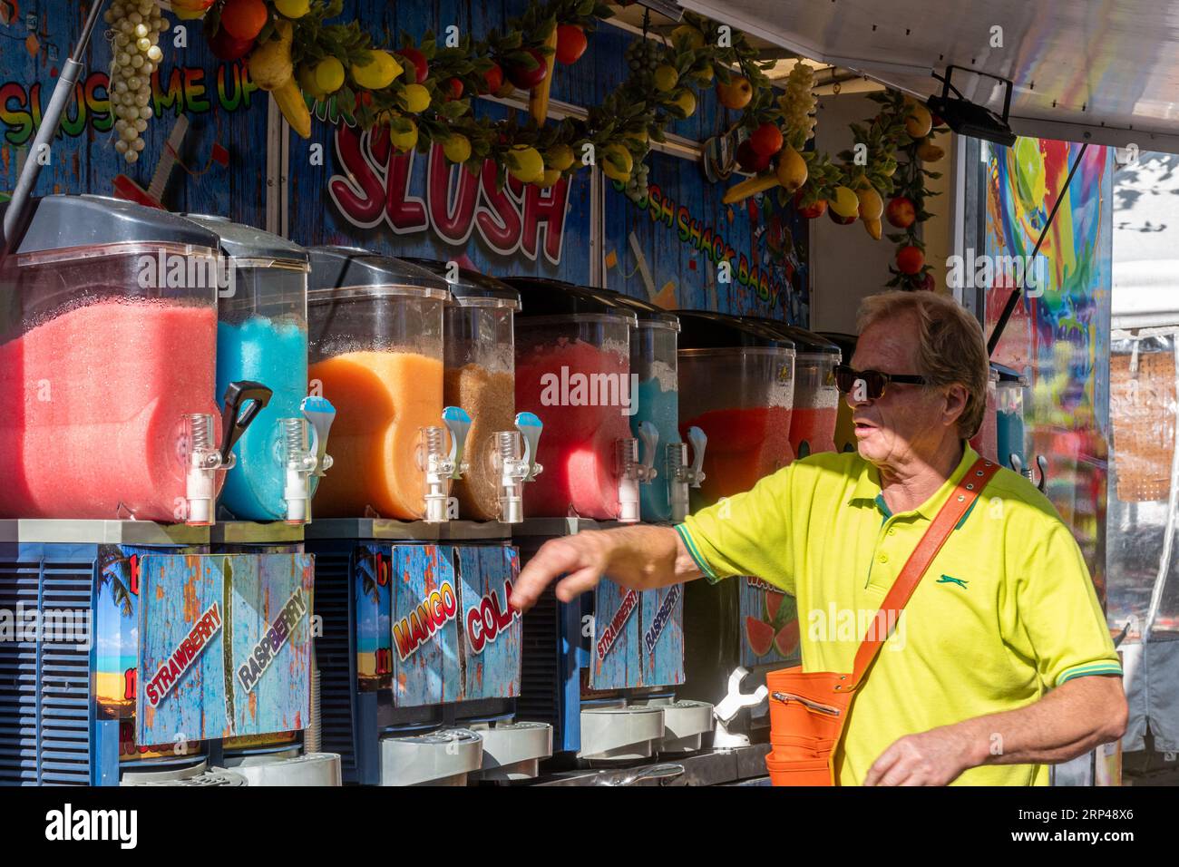Slush stand with man selling colourful ice cold slushy fruit drinks at a market in Surrey, England, UK Stock Photo
