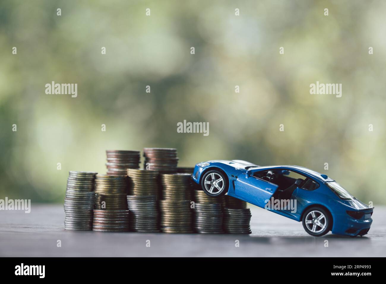 Saving money for car, Finance and car loan, Investment and business concept. Miniature car model with growing stack of coins money on nature green bac Stock Photo