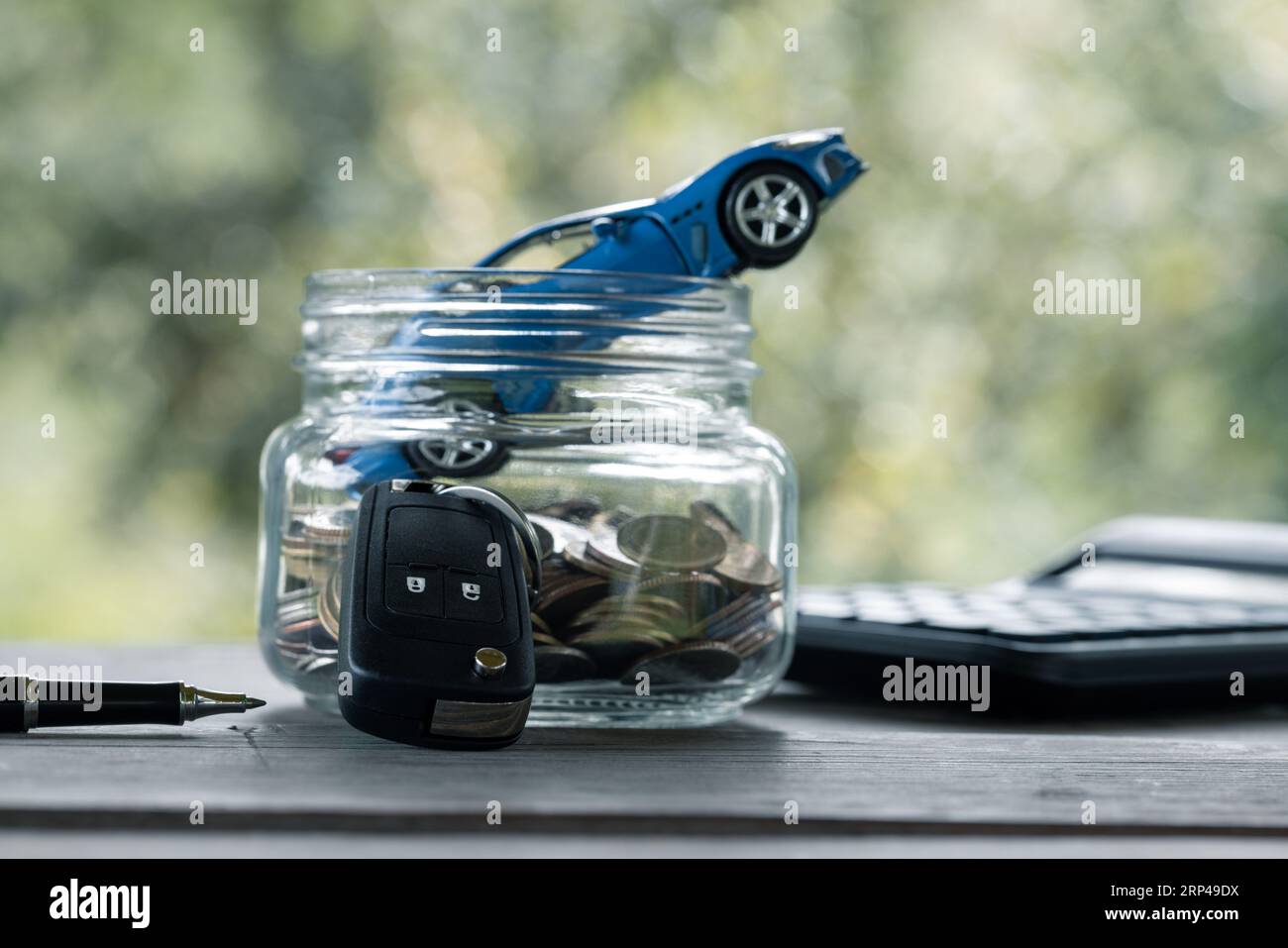 Saving money for car, Finance and car loan, Investment and business concept. Miniature car model in jar with coins on nature green background. Stock Photo