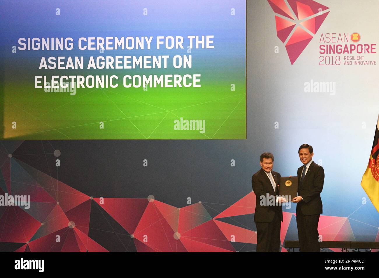 (181112) -- SINGAPORE, Nov. 12, 2018 -- Singaporean Minister for Trade and Industry Chan Chun Sing (R) hands over the signed document to ASEAN Secretary General Lim Jock Hoi during the signing ceremony of ASEAN s agreement on e-commerce, in Singapore, on Nov. 12, 2018. Trade ministers of the Association of Southeast Asian Nations (ASEAN) member states signed an agreement on e-commerce on Monday, encouraging paperless trading between businesses and governments of the bloc to generate rapid and efficient transactions. ) (nxl) SINGAPORE-ASEAN-E-COMMERCE-AGREEMENT ThenxChihxWey PUBLICATIONxNOTxINx Stock Photo