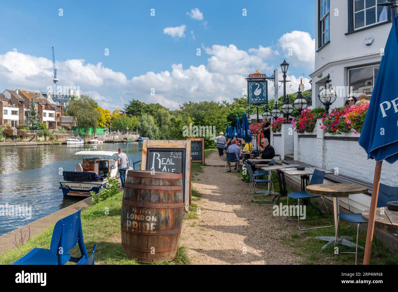 The Swan Hotel, a riverside pub by the river Thames in Staines-upon-Thames, Surrey, England, UK, with moored boats and people outside having drinks Stock Photo