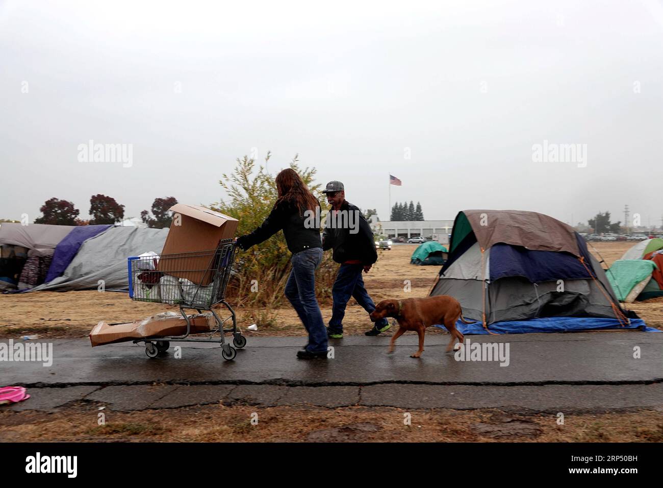 (181122) -- BUTTE, Nov. 22, 2018 (Xinhua) -- Residents walk near the tents at a parking lot in Chico of Butte County, California, the United States, Nov. 21, 2018. Local officials warned that the rain after the wildfire could cause risk of flash floods and mudflows. (Xinhua/Wu Xiaoling)(clq) U.S.-CALIFORNIA-BUTTE-WILDFIRE-RAIN PUBLICATIONxNOTxINxCHN Stock Photo