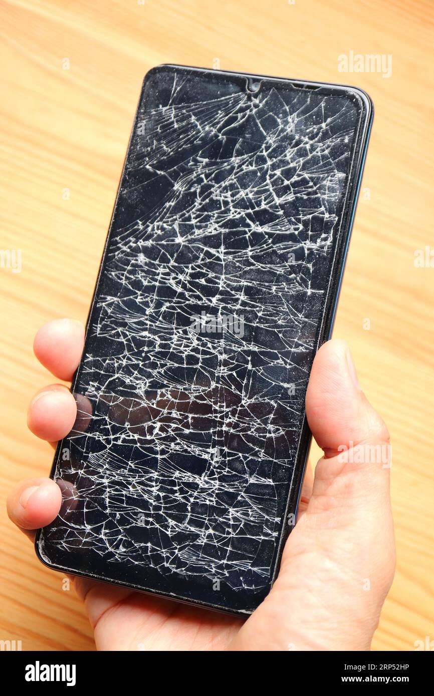 Hand holding a phone with broken screen Stock Photo