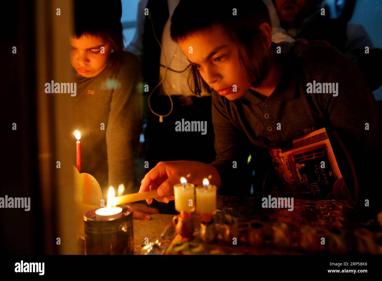 (181203) -- JERUSALEM, Dec. 3, 2018 -- An ultra-Orthodox Jewish young man lights a candle during Hanukkah in Mea Shearim neighborhood in Jerusalem, on Dec. 3, 2018. Hanukkah, also known as the Festival of Lights and Feast of Dedication, is an eight-day Jewish holiday commemorating the rededication of the Holy Temple (the Second Temple) in Jerusalem at the time of the Maccabean Revolt against the Seleucid Empire of the 2nd Century B.C. ) MIDEAST-JERUSALEM-HANUKKAH GilxCohenxMagen PUBLICATIONxNOTxINxCHN Stock Photo