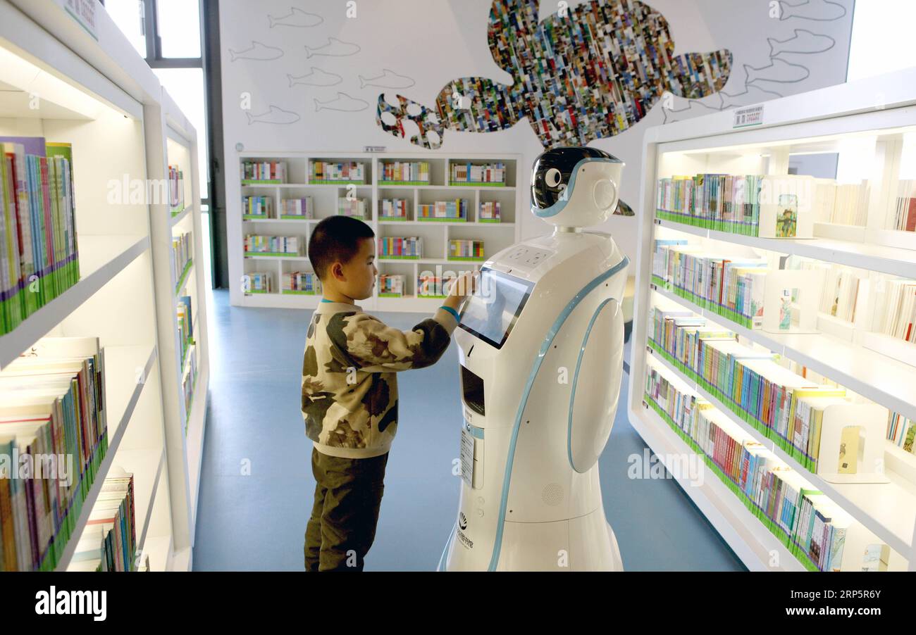 (181221) -- TIANJIN, Dec. 21, 2018 (Xinhua) -- A kid interacts with a robotic server at a library in the Sino-Singapore Tianjin eco-city in Binhai New Area, north China s Tianjin, Dec. 19, 2018. The Sino-Singapore Tianjin eco-city, inaugurated in 2008, is an intergovernmental cooperation project designed to strengthen environmental protection, conserve resources and build a harmonious society. The eco-city is expected to be a model for other cities in China. (Xinhua/Zheng Wei) CHINA-TIANJIN-SINO-SINGAPORE ECO CITY-DECADE-NEW LOOK (CN) PUBLICATIONxNOTxINxCHN Stock Photo