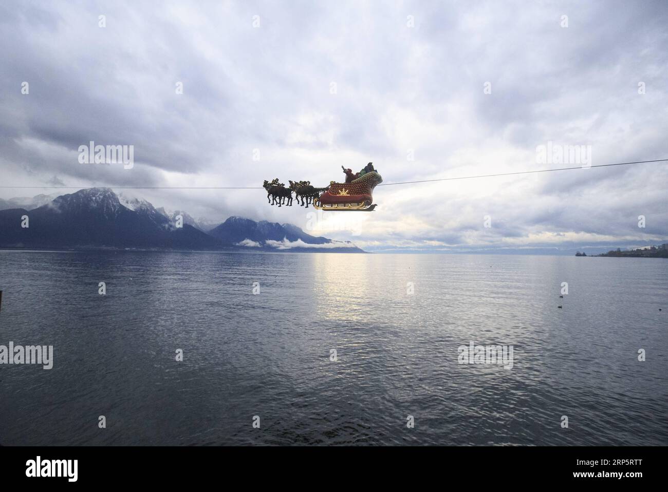 (181222) -- MONTREUX (SWITZERLAND), Dec. 22, 2018 -- A Santa Claus waves to the crowd from his flying sleigh drawn by reindeers over Lake Leman at sunset in Montreux, Switzerland, on Dec. 22, 2018. The flying Santa Claus stunt show is part of promotional activities by the Christmas market in Montreux, which is one of the most famous and biggest markets of its kind in Switzerland. ) SWITZERLAND-MONTREUX-SANTA CLAUS-FLYING SLEIGH XuxJinquan PUBLICATIONxNOTxINxCHN Stock Photo