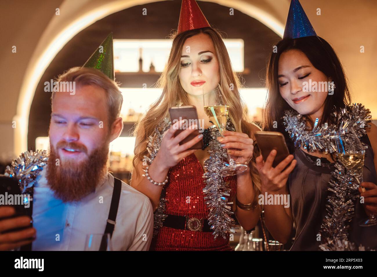 Diverse friends busy in using their mobile phone in the party Stock Photo