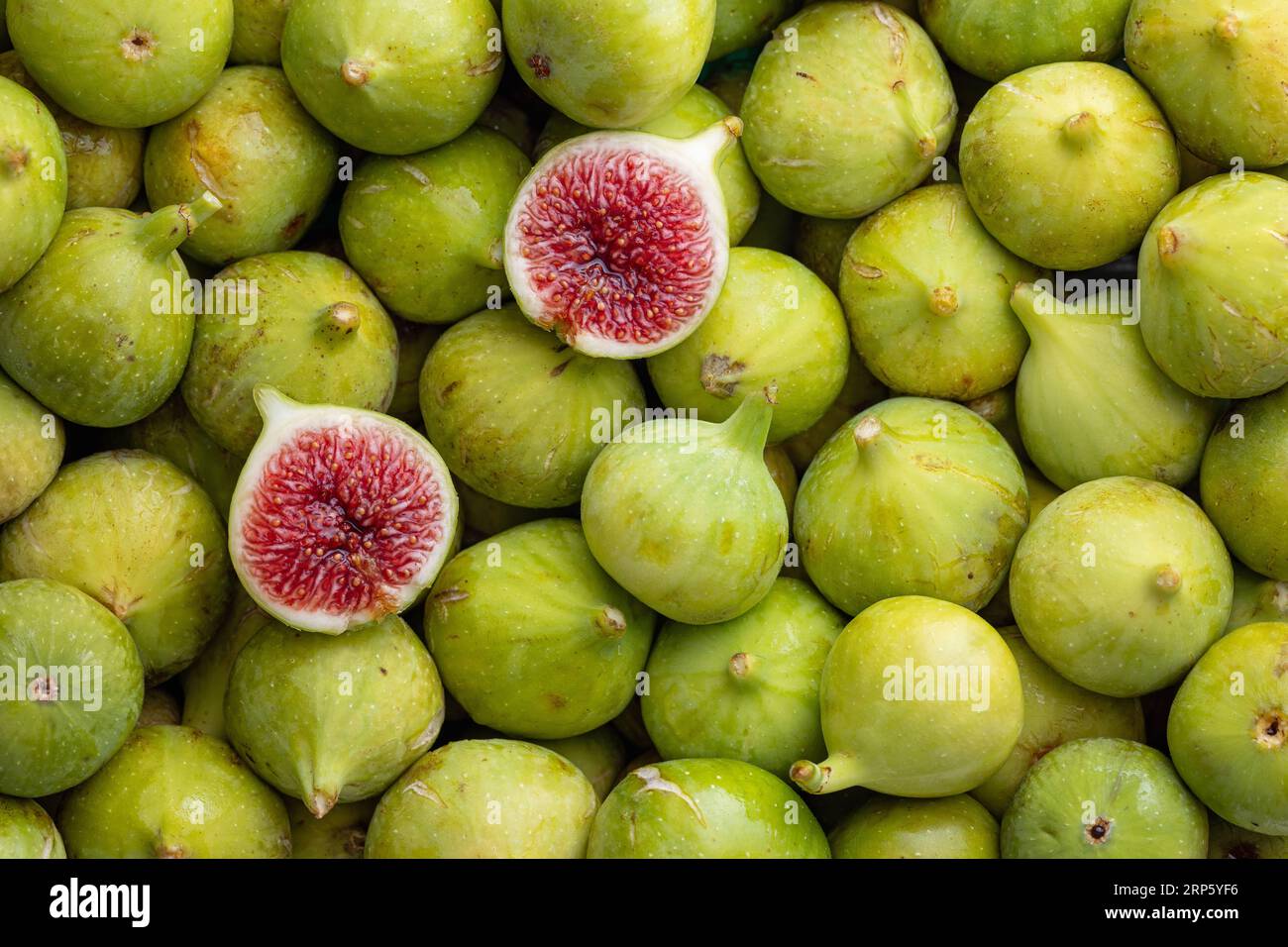 Pile of fresh, honey sweet, green figs, one cut open. Raw green oganic