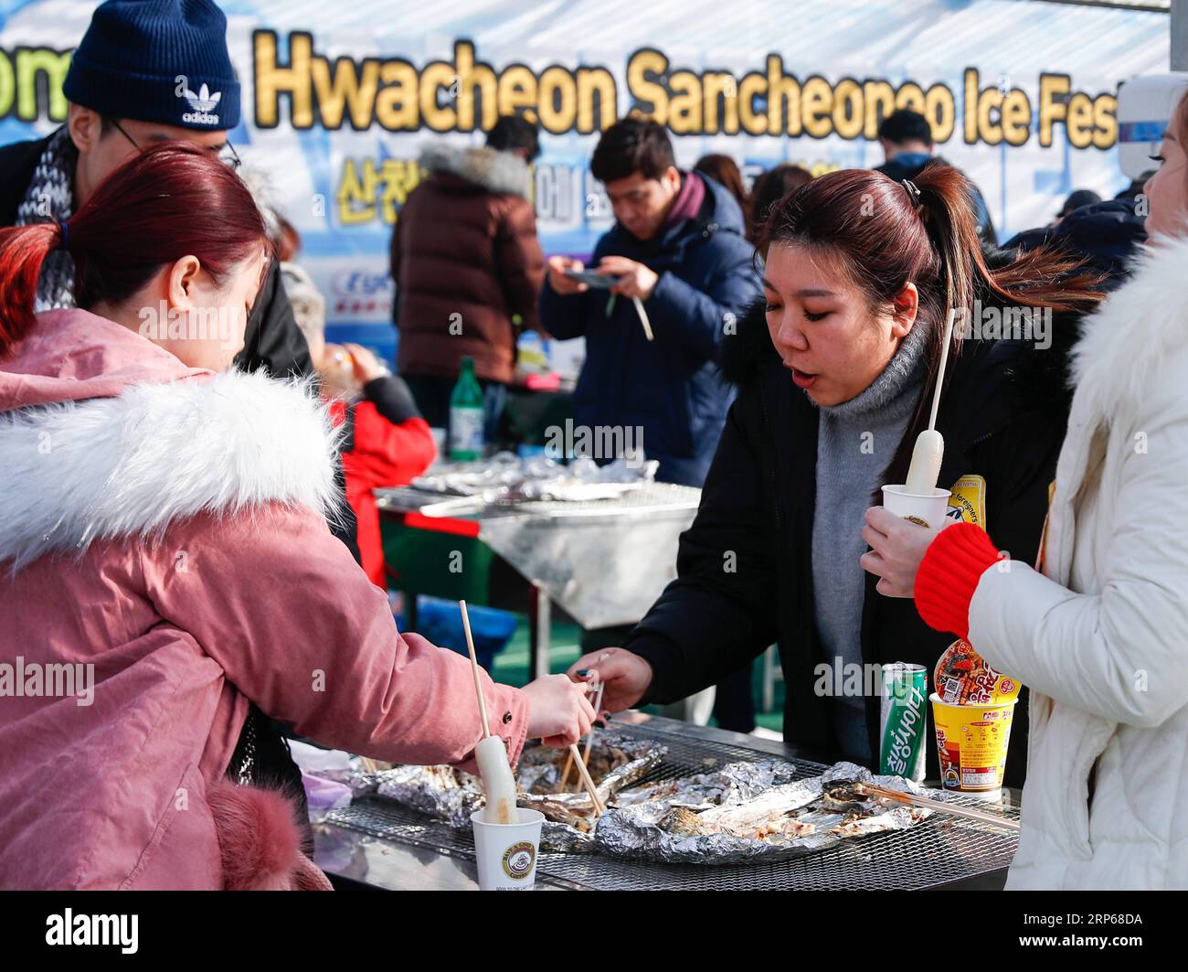 (190105) -- HWACHEON, Jan. 5, 2019 -- People enjoy grilled trouts by the side of a frozen river during the Sancheoneo Ice Festival in Hwacheon, South Korea, Jan. 5, 2019. As one of the biggest winter events in South Korea, the annual three-week festival draws people to the frozen Hwacheon river, where organizers drill fishing holes in the ice and release trouts into the river during the festival period. This year the festival lasts from Jan. 5 to Jan. 27. ) SOUTH KOREA-HWACHEON-SANCHEONEO ICE FESTIVAL WangxJingqiang PUBLICATIONxNOTxINxCHN Stock Photo