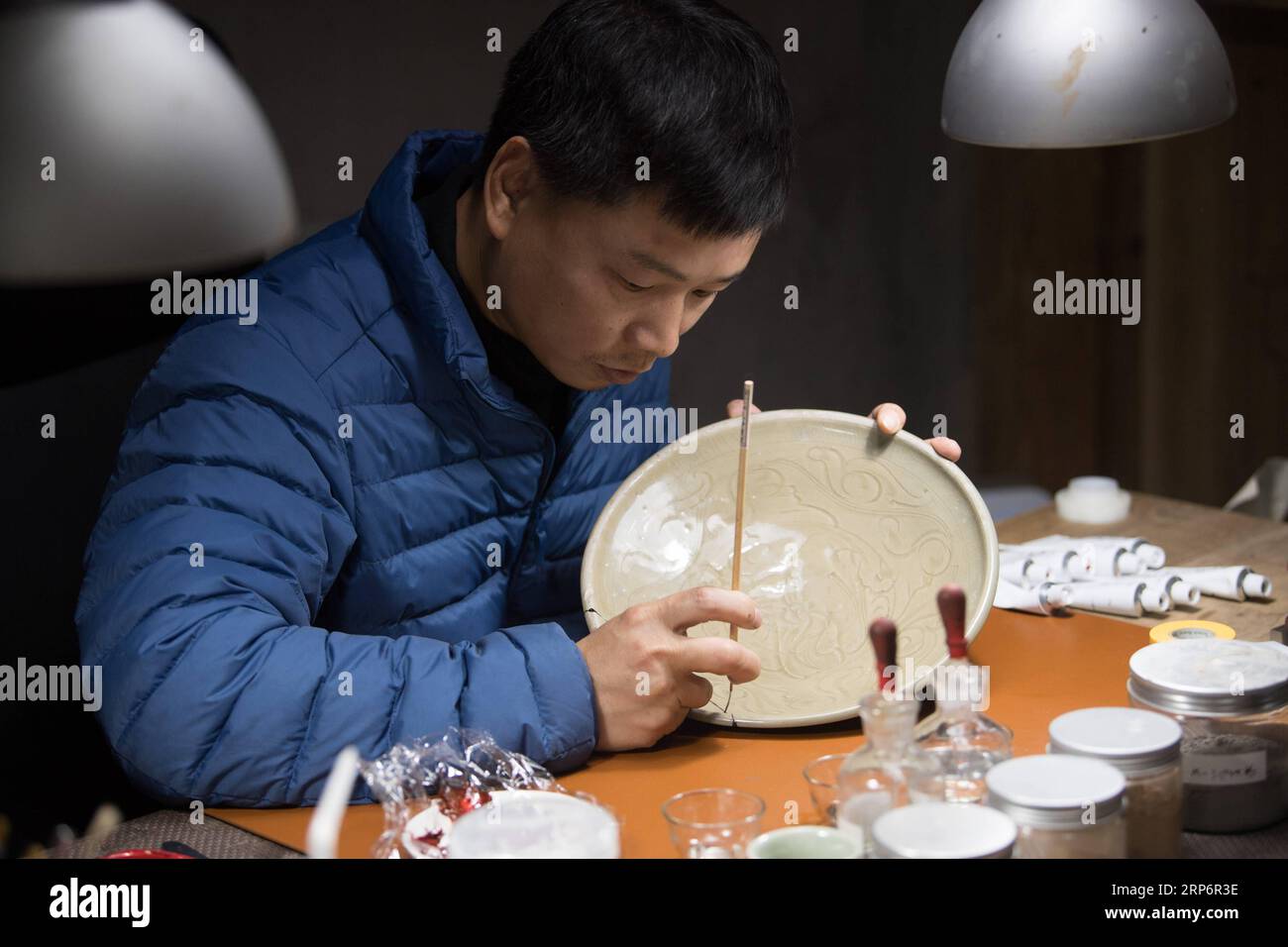 (190119) -- LONGQUAN, Jan. 19, 2019 (Xinhua) -- Wu Rongqiang repairs a celadon ware with lacquer at his studio in Niutouling Village, Longquan City of east China s Zhejiang Province, Jan. 15, 2019. Wu Rongqiang, a Longquan native aged 45, started exploring traditional lacquer art since 2012. In 2017, he moved his family to an old house deep in the mountains in Longquan in order to do more experiments in lacquer undisturbed. He uses lacquer to repair broken porcelain and to create lacquerware. Also, he experiments on the production of various lacquers. I feel so pleased to return to my hometown Stock Photo