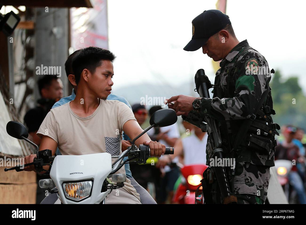 (190120) -- COTABATO CITY, Jan. 20, 2019 -- A policeman from the Philippine National Police inspects the identification cards of motorists during a security check at a road in Cotabato City, the Philippines, Jan. 20, 2019. Muslim Filipinos will cast their vote on Monday to ratify the landmark Bangsamoro Organic Law (BOL), a law that will pave the way for wider self-rule to the Muslim minority in the Philippines and is hoped to end the decades-old conflict in southern Philippines. ) PHILIPPINES-COTABATO CITY-BOL-SECURITY ROUELLExUMALI PUBLICATIONxNOTxINxCHN Stock Photo